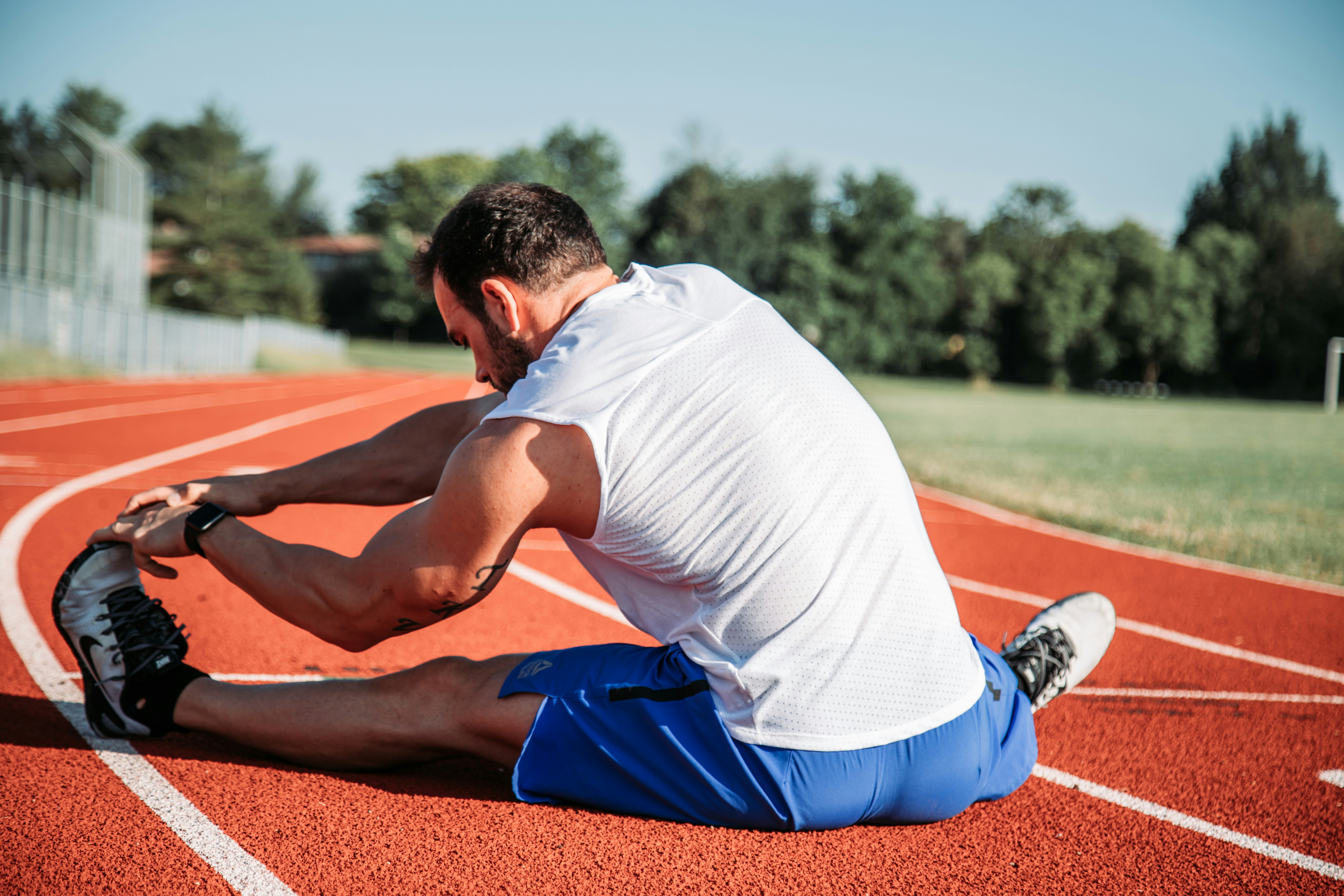an athletic man stretching in a track field